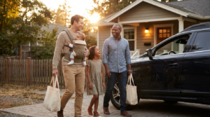 a family walking from their SUV towards their house