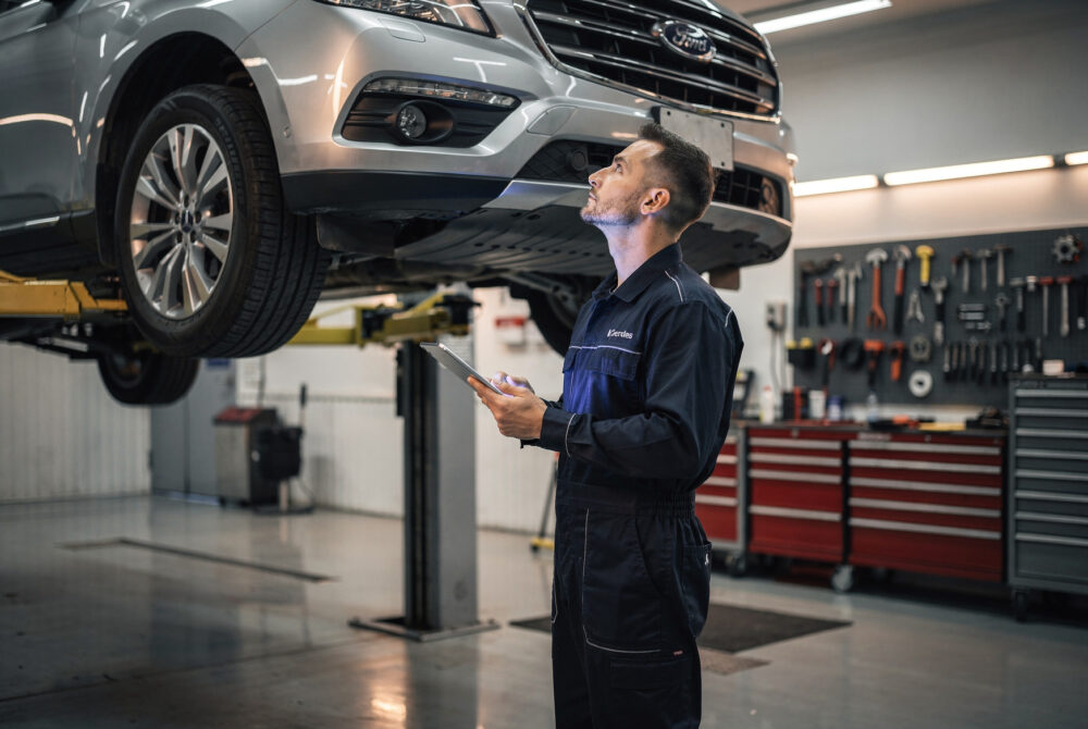 Technician inspecting an SUV transmission on a lift during a Ford transmission recall repair.